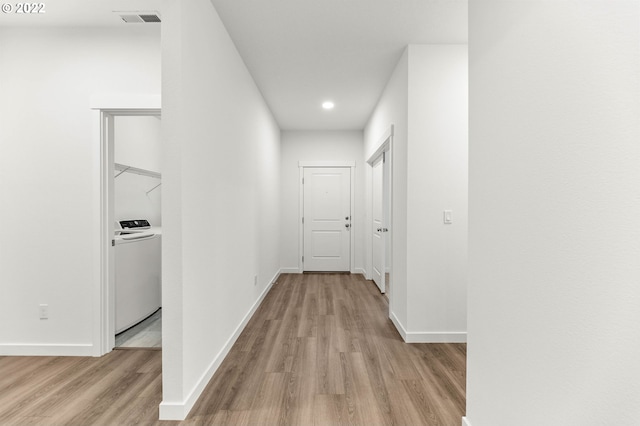 hall with light wood-type flooring and washer / dryer