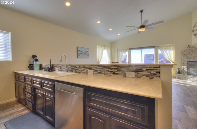 kitchen with dishwasher, sink, wood-type flooring, lofted ceiling, and a fireplace