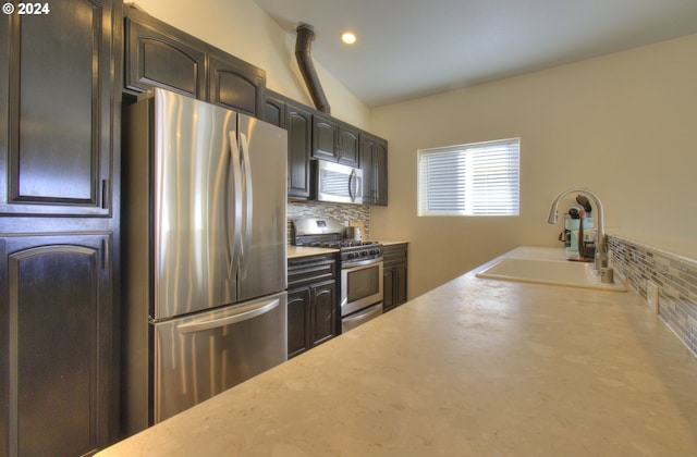 kitchen featuring vaulted ceiling, sink, stainless steel appliances, and tasteful backsplash