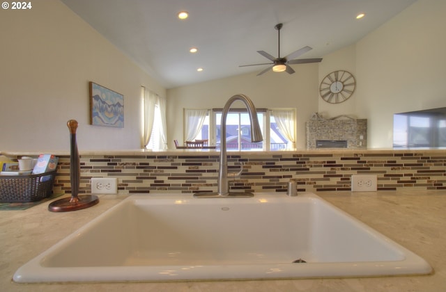 interior details featuring decorative backsplash, a stone fireplace, ceiling fan, and sink