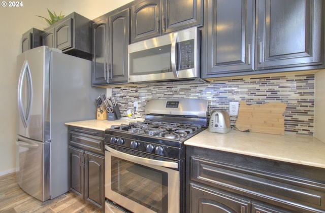 kitchen with light wood-type flooring, appliances with stainless steel finishes, and tasteful backsplash