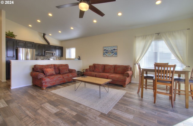 living room with plenty of natural light, dark wood-type flooring, and vaulted ceiling