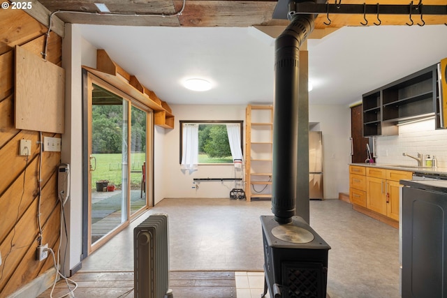 interior space with a wood stove, backsplash, sink, range, and stainless steel refrigerator