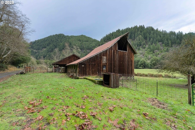 view of property exterior featuring central air condition unit, a mountain view, an outbuilding, and a rural view