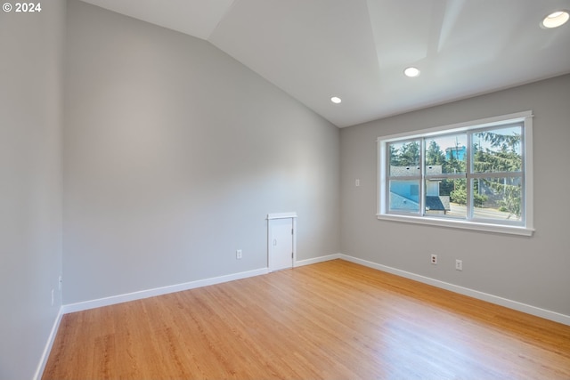 empty room with light wood-type flooring and vaulted ceiling