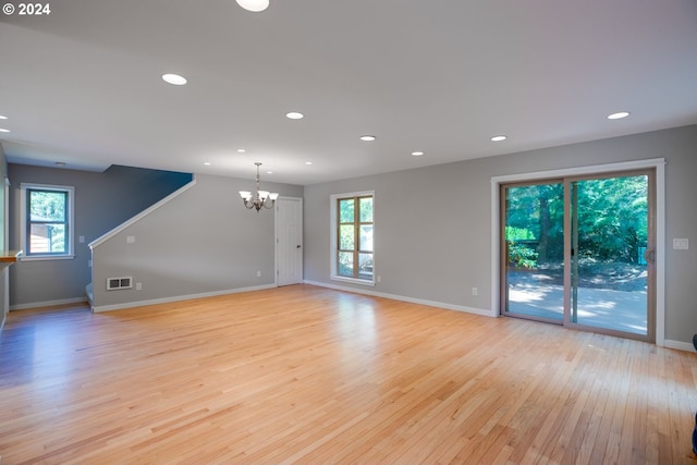 empty room featuring a notable chandelier and light hardwood / wood-style flooring