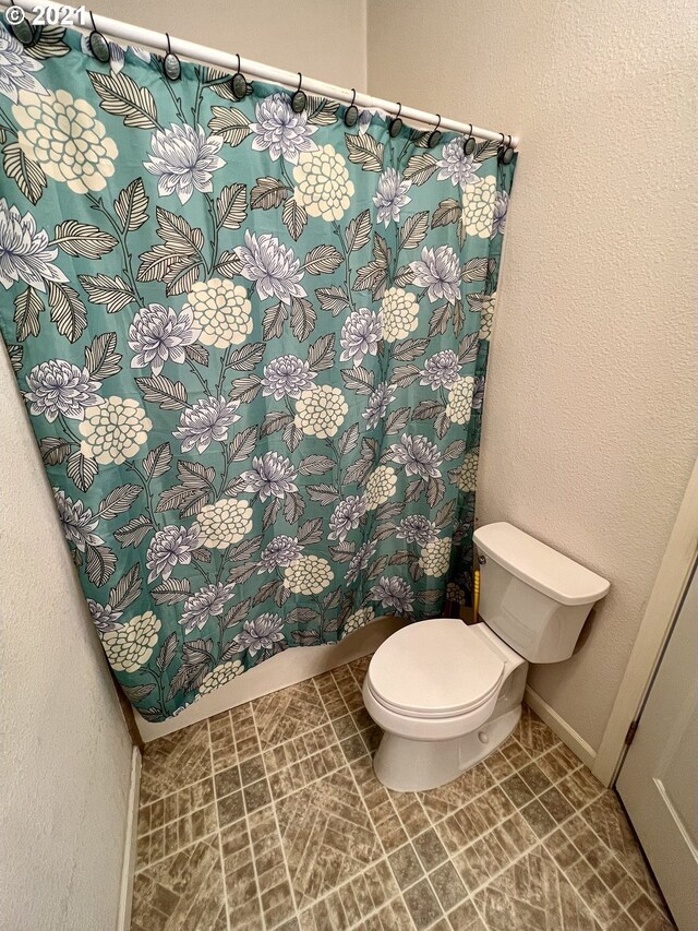 95851 Mckinnon Dr, Gold Beach, OR 97444 - bathroom featuring baseboards, toilet, and curtained shower