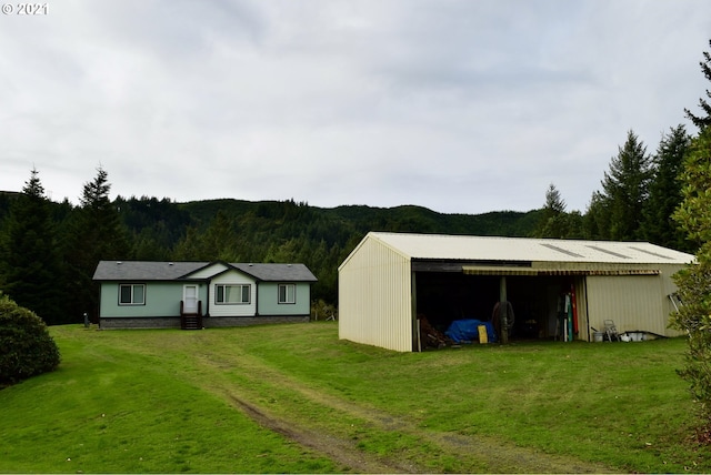 95851 Mckinnon Dr, Gold Beach, OR 97444 - exterior space with a pole building, a front yard, a forest view, an outdoor structure, and driveway