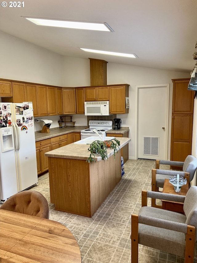 kitchen featuring vaulted ceiling, a kitchen island, and white appliances