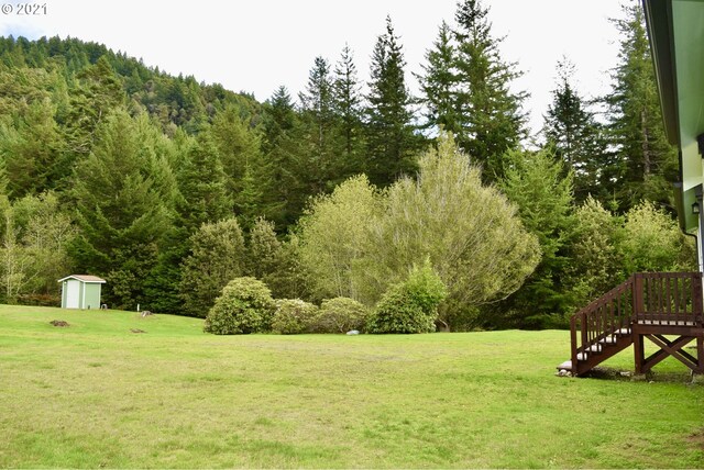95851 Mckinnon Dr, Gold Beach, OR 97444 - view of yard featuring an outbuilding, a view of trees, a storage shed, and stairway