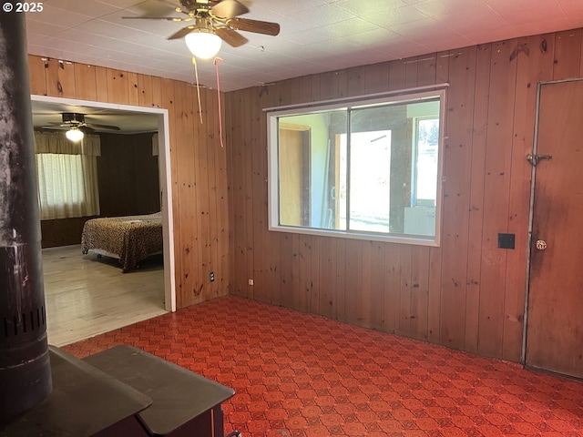 spare room featuring ceiling fan and wooden walls