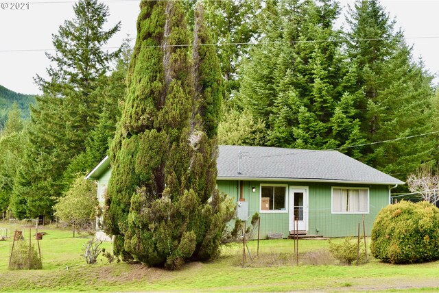 95851 Mckinnon Dr, Gold Beach, OR 97444 - ranch-style house featuring a wooded view, a shingled roof, and a front yard