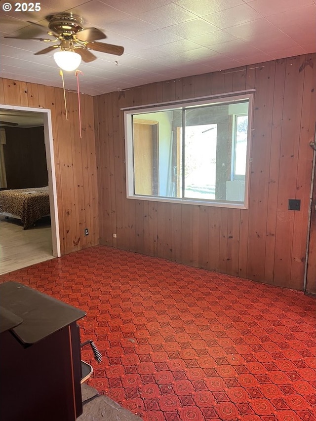 unfurnished room with light carpet, ceiling fan, and wood walls