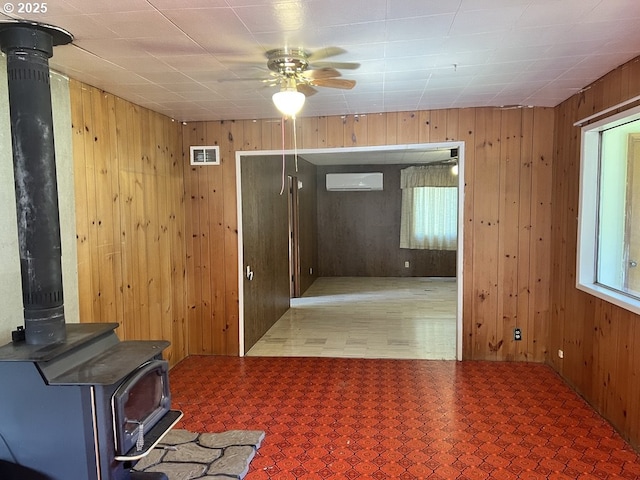 95851 Mckinnon Dr, Gold Beach, OR 97444 - interior space with visible vents, a wood stove, ceiling fan, wooden walls, and an AC wall unit