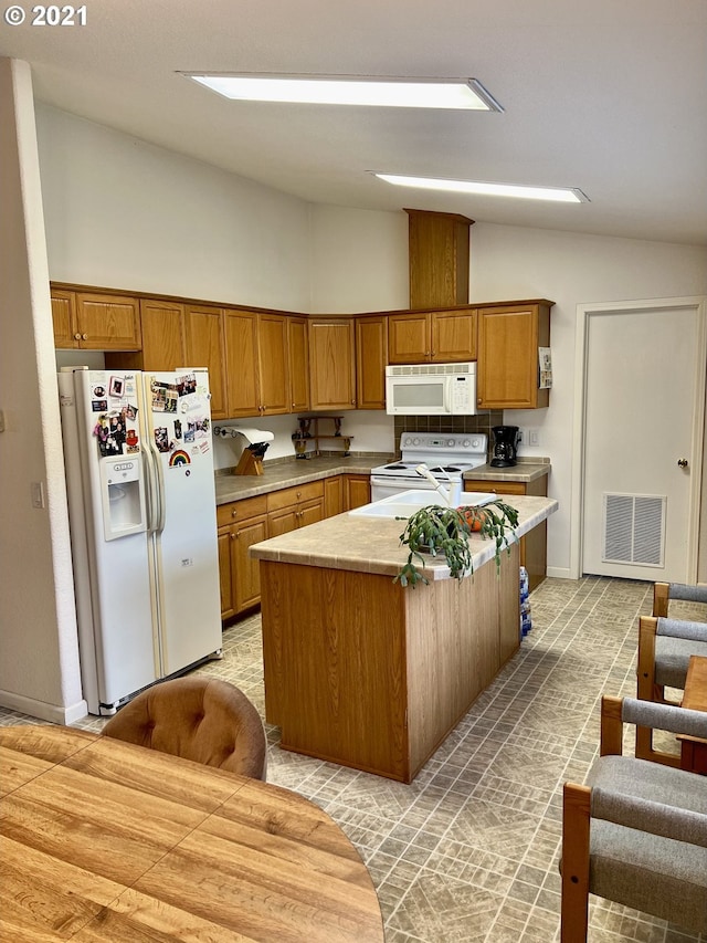 kitchen featuring vaulted ceiling, a center island, and white appliances