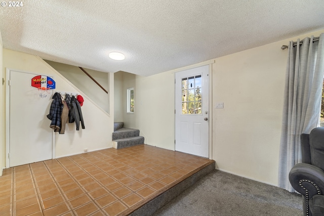 carpeted foyer entrance featuring a textured ceiling