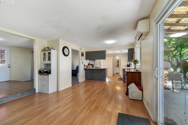 interior space with white cabinetry, plenty of natural light, a wall mounted AC, and light hardwood / wood-style flooring