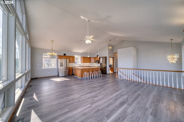 interior space with ceiling fan with notable chandelier, hardwood / wood-style flooring, stainless steel appliances, and a kitchen breakfast bar