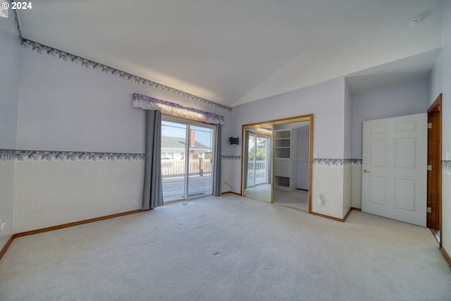 carpeted spare room featuring vaulted ceiling