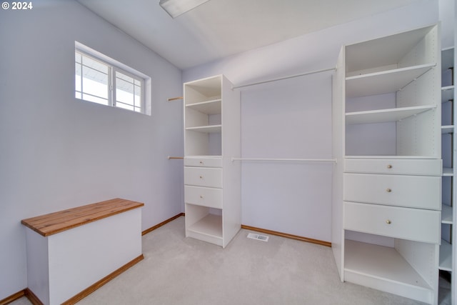 walk in closet featuring light colored carpet