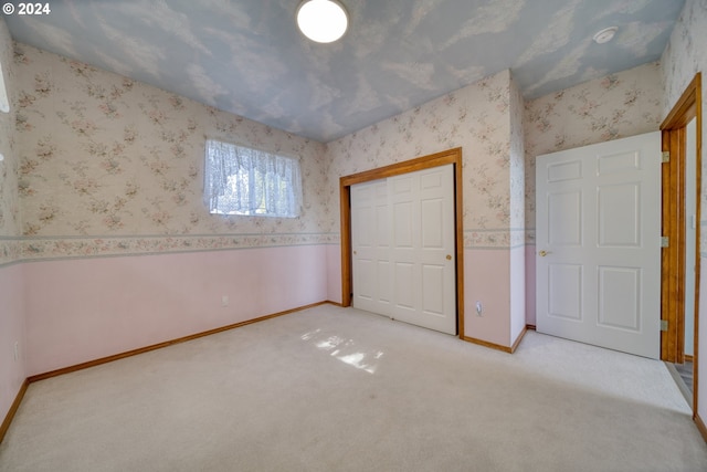 unfurnished bedroom with light colored carpet and a closet