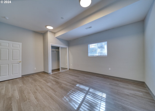 unfurnished bedroom with a closet and light hardwood / wood-style floors