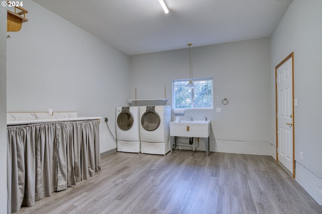 clothes washing area featuring light hardwood / wood-style floors, washing machine and dryer, and sink