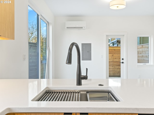 room details with light brown cabinets, electric panel, an AC wall unit, and sink