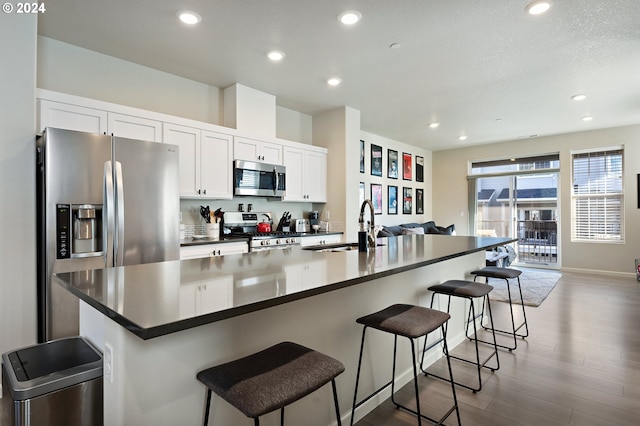 kitchen featuring white cabinets, an island with sink, a breakfast bar, and stainless steel appliances