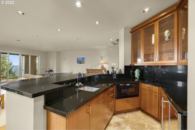 kitchen featuring kitchen peninsula, backsplash, light tile flooring, dark stone countertops, and black oven