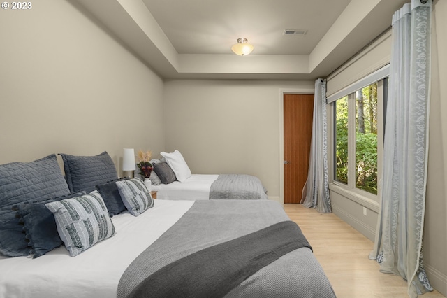 bedroom featuring a raised ceiling and light hardwood / wood-style floors