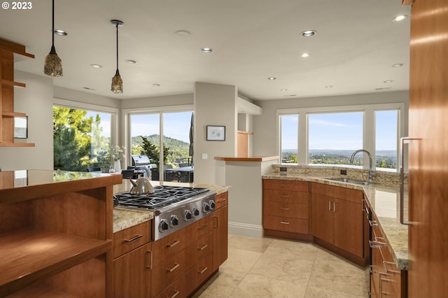 kitchen with light stone countertops, decorative light fixtures, stainless steel gas cooktop, light tile flooring, and sink