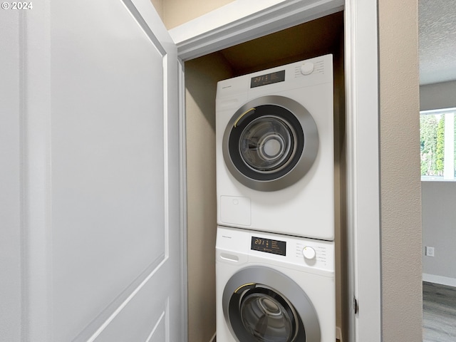 laundry room with hardwood / wood-style flooring and stacked washer / dryer