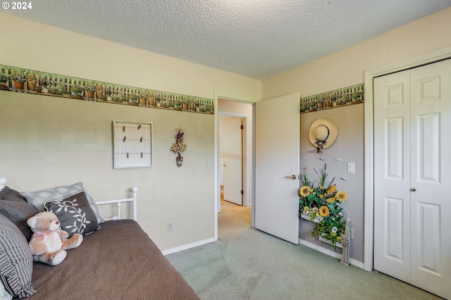 carpeted bedroom featuring a textured ceiling and a closet