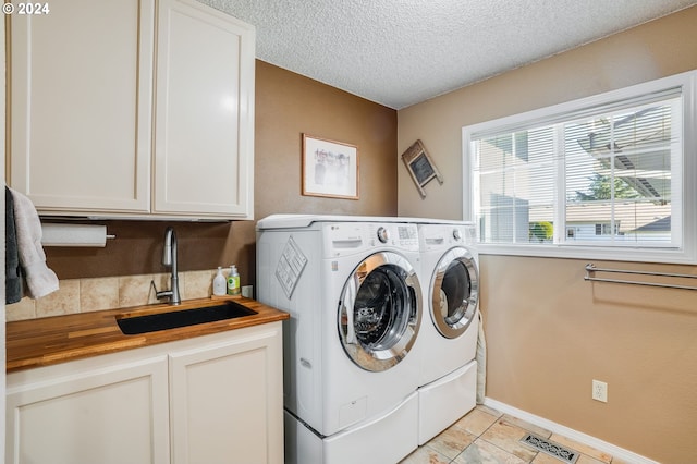 washroom featuring light tile patterned flooring, a textured ceiling, cabinets, sink, and washing machine and clothes dryer