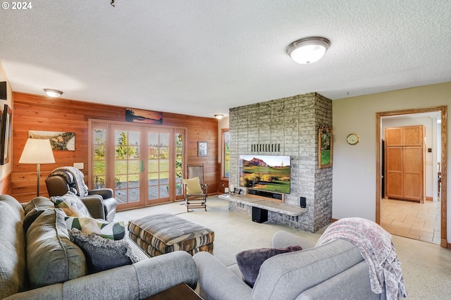 living room featuring a textured ceiling, a fireplace, carpet floors, and wooden walls