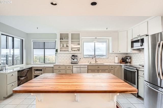 kitchen with appliances with stainless steel finishes, butcher block countertops, sink, and a center island