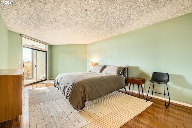 bedroom featuring a textured ceiling, access to exterior, and light hardwood / wood-style flooring