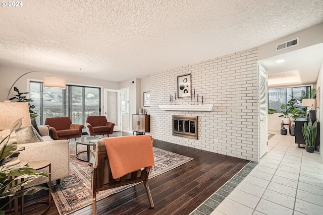 living room featuring hardwood / wood-style floors, a textured ceiling, and a brick fireplace