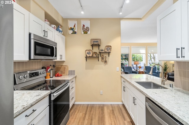 kitchen with stainless steel appliances, light hardwood / wood-style floors, tasteful backsplash, and sink