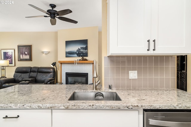 kitchen with backsplash, a tiled fireplace, open floor plan, and a sink