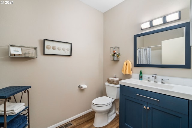 bathroom with hardwood / wood-style floors, a shower with curtain, toilet, and vanity