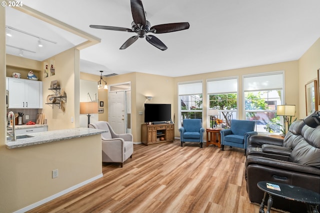 living room featuring light hardwood / wood-style flooring, ceiling fan, track lighting, and sink