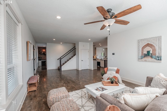 living room featuring ceiling fan, dark wood-type flooring, and a textured ceiling