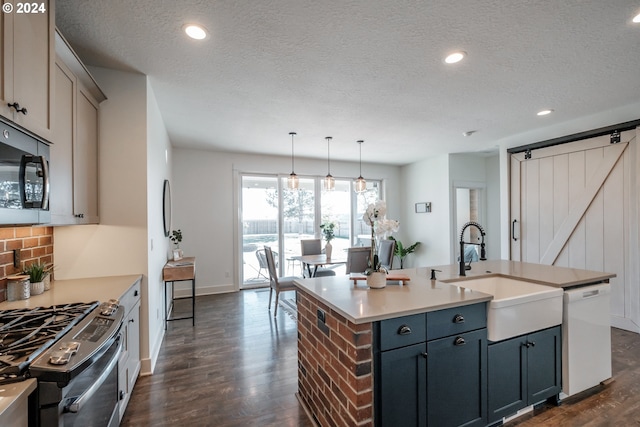 kitchen with dark hardwood / wood-style flooring, sink, appliances with stainless steel finishes, and an island with sink