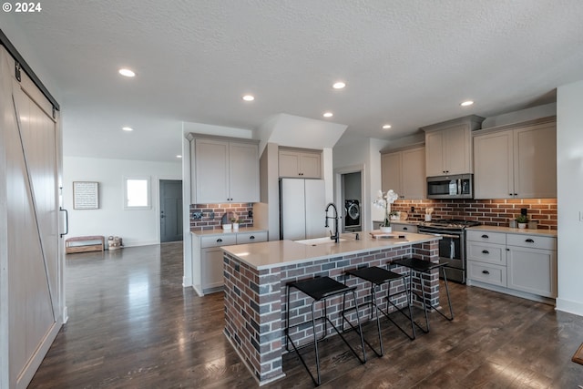 kitchen featuring stainless steel appliances, tasteful backsplash, dark hardwood / wood-style floors, a breakfast bar area, and a center island with sink