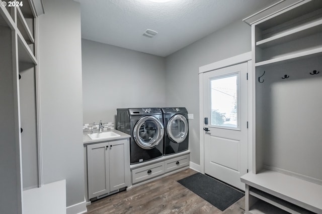 clothes washing area featuring cabinets, a textured ceiling, sink, separate washer and dryer, and dark hardwood / wood-style floors