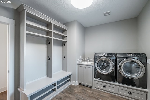 laundry room featuring sink, cabinets, separate washer and dryer, dark hardwood / wood-style floors, and a textured ceiling