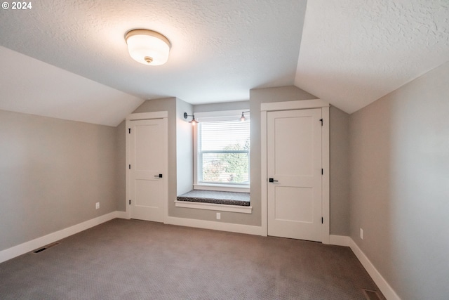 bonus room featuring carpet flooring, vaulted ceiling, and a textured ceiling