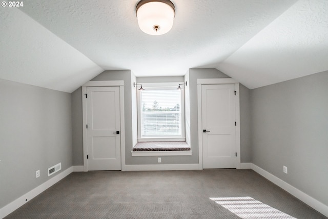 bonus room with carpet flooring, a textured ceiling, and lofted ceiling